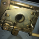 This is how the trunk release works, taken with the magic of cameraphones. Looking from beneath you can see the latch in the center, with the quarter-moon like latch extending into its hole to hold the trunk lid in place. The cable reaches through along the bottom and is secured on the left with a screw coming in from above. Pull the cable and it slides the latch back. The return spring pulls everything to its original location. Pull it over and over and the cable stretches, so unscrew the lock screw, pull the cable tight, and crank that screw back down.
